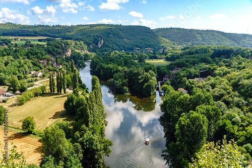 France. Lot. Saint-Cirq-Lapopie. A view looking down over the Lot River, where a tourist gabare a traditional boat used for exploring the valley is sailing