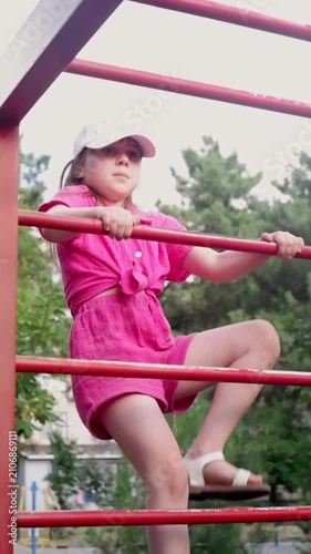 Active child playing and climbing on a jungle gym ladder at an outdoor public park playground