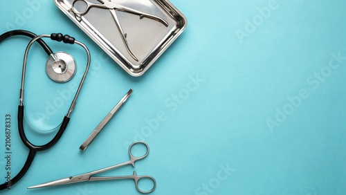 Medical examination concept with stethoscope and surgical tools on blue