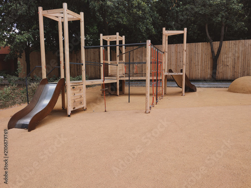 A modern, safe playground in a park with rubber surfacing made from recycled materials. Shock-absorbing rubber flooring in a public park.