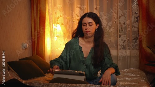 Beautiful young Caucasian woman using a tablet with an irritated expression while searching for a suitable movie. Online entertainment, streaming platforms, digital lifestyle