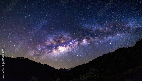 Night sky vista over a dark, forested, hilly landscape reveals a radiant Milky Way
