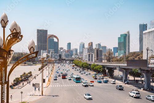 Bustling urban landscape of Addis Ababa, Ethiopia, featuring modern skyscrapers, vibrant multi-lane traffic, and ornate street lamps under a bright sky.