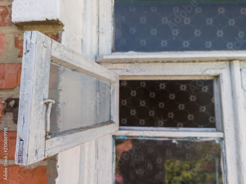 Open old white wooden window frame on brick wall