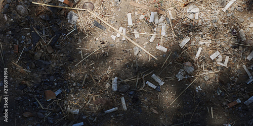 Debris covers the ground, including small rocks, dry grass, and many white firecracker wrappers creating a scattered, unkempt surface