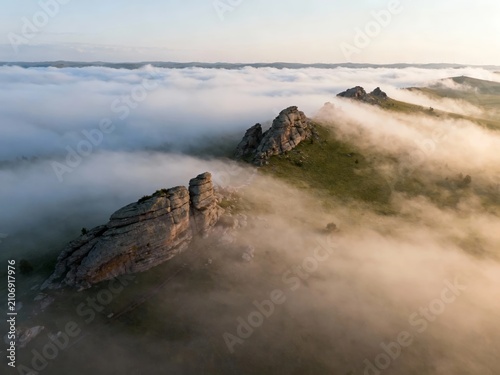 Aerial view of rocky mountain peaks emerging from a sea of clouds at dawn