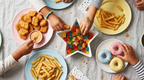 Children eating snacks like chicken nuggets, fries, and donuts at a table