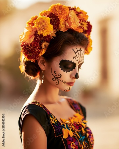 elegant woman wearing traditional Day of the Dead makeup and floral crown, embroidered Mexican dress, marigold petals, soft golden sunlight, authentic cultural portrait, ultra realistic photography
