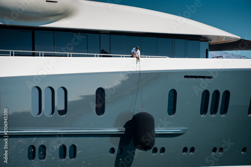 Foto Detail of beautiful Superyacht, deckhand lifting the huge fender of the starboar