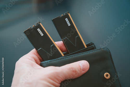 Black DDR5 RAM modules inside a black wallet held in hand, symbolizing high cost and value of memory for AI training.