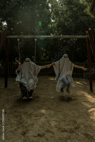 People in Ghost Costumes Sitting on Playground Swings