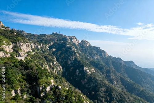 A panoramic view of rugged mountain ranges covered in green vegetation under a clear blue sky