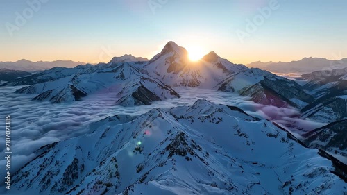 Sunrise over snow covered mountain peaks with sea of clouds