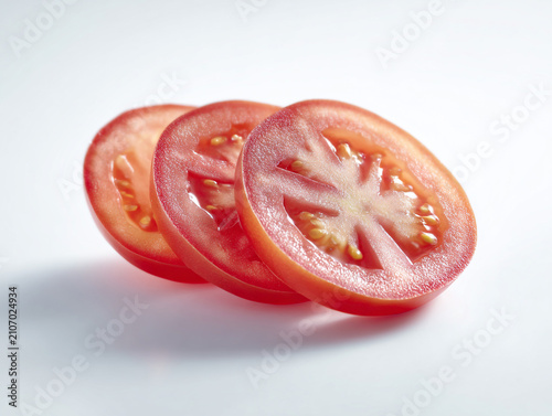 Photorealistic studio product photography of fresh red tomato slices with seeds, isolated on a clean white background with minimalist high-key lighting.