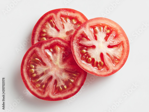 Photorealistic studio product photography of fresh red tomato slices with seeds, isolated on a clean white background with minimalist high-key lighting.
