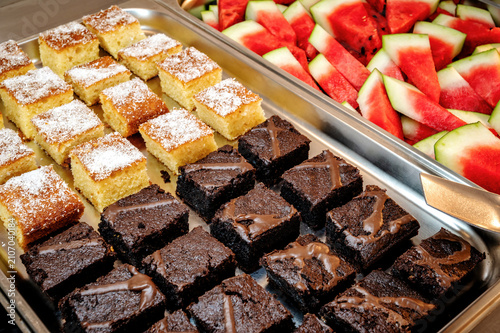 Freshly prepared dessert selection with chocolate brownies, coconut sponge cake and juicy watermelon served at a luxury hotel buffet.