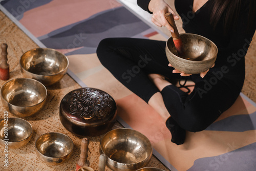 Canvastavla Close-up of a woman's hands sitting in a lotus position using a singing bowl indoors