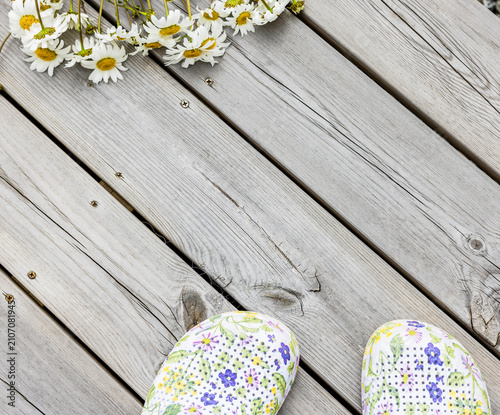 Margeritenstrauss auf eienm Holzboden und Gartenschuhen