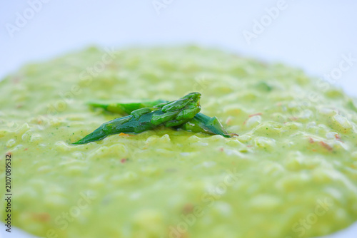 Close‑up of creamy asparagus risotto garnished with fresh asparagus tips, highlighting smooth texture and vibrant green color in a minimalist gourmet presentation.