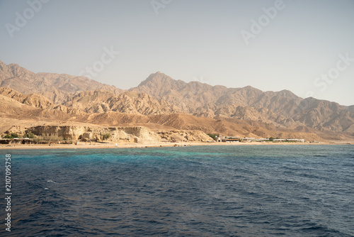 Desert mountains meeting the clear turquoise waters of the red sea