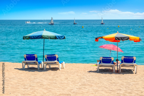View of sea and  sandy beach with colourful umbrellas at seaside of Costa Brava. Catalonia, Spain