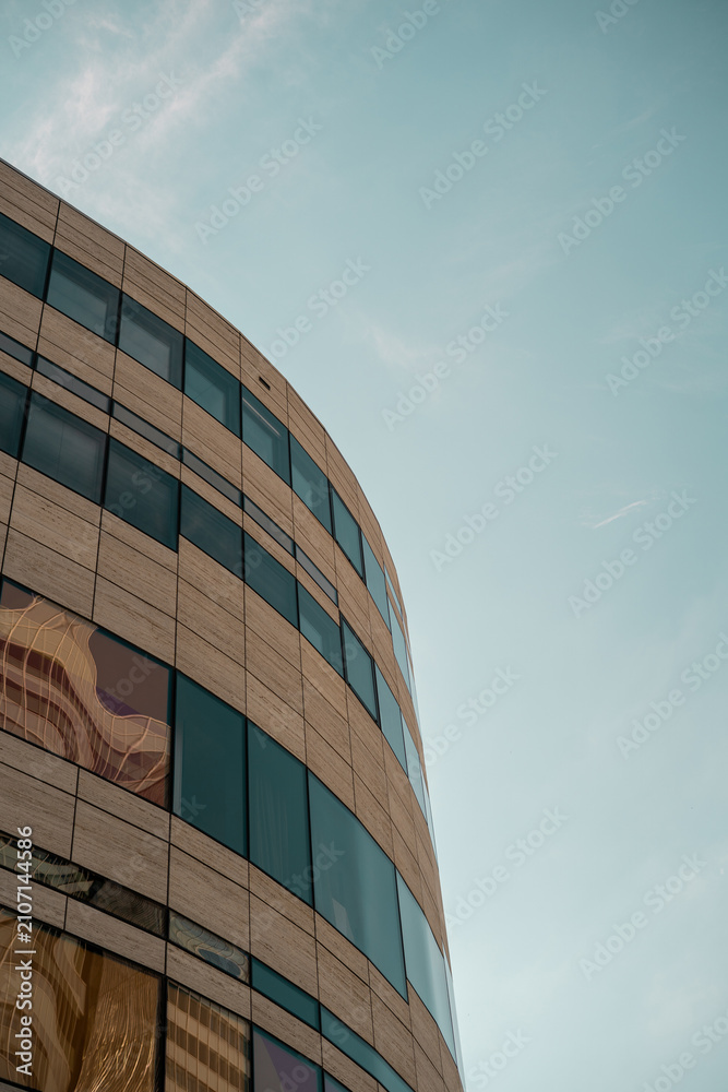 Obraz premium Curved stone and glass facade of a modern office building, minimalist architectural detail