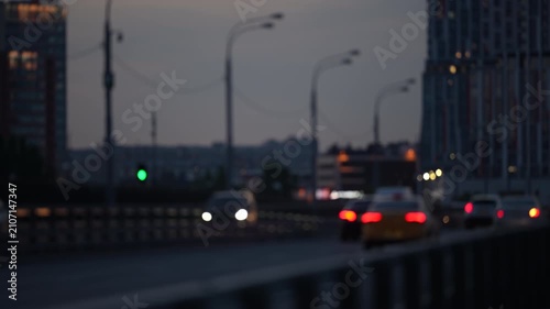 Blurred urban traffic scene with glowing car lights at dusk, city road and modern buildings creating dynamic motion and metropolitan atmosphere