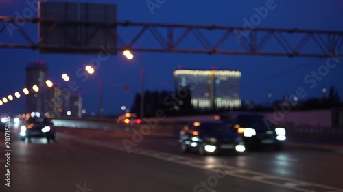Blurred urban road with moving cars and glowing headlights at dusk, modern city traffic atmosphere showing transportation, mobility and motion concept
