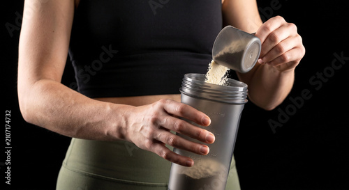 Foto Athletic Woman Adding Scoop of Protein Powder to Shaker Bottle