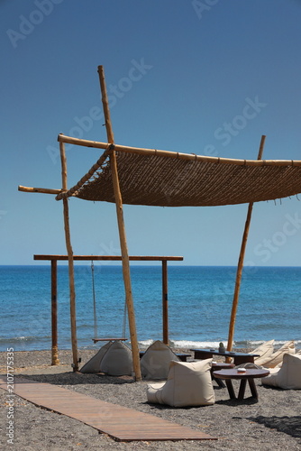 A luxurious beach scene with a beach umbrella and lounge chairs in Santorini, Greece
