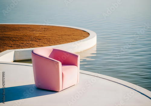 Modern pink armchair positioned on a white architectural structure overlooking calm water minimalist outdoor furniture design
