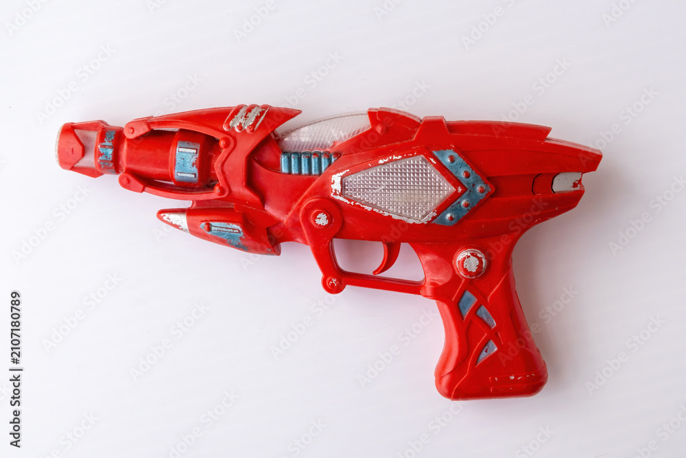 Naklejka premium Red vintage plastic toy ray gun with sci-fi design isolated on white background. Space blaster toy pistol for children play, gaming, and leisure activity.