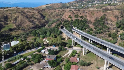 Aerial push in panoramic view of highway overpass toward tunnels