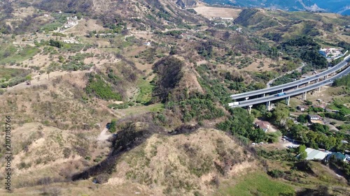Aerial view of mountain highway bridge over plain near distant dam