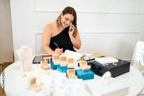 Jewelry designer woman talking on phone and writing, managing small business