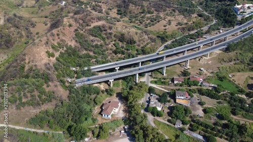 Aerial view of dual highway bridge over village ending in tunnel