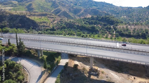 Aerial wide angle pan of heavy highway bridge with protective guardrails