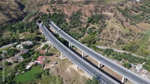 Aerial orbit view of highway overpass and tunnels in mountain valley