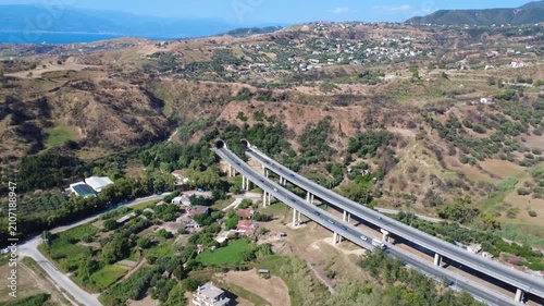 Aerial view of dual highway bridge with traffic exiting mountain tunnel