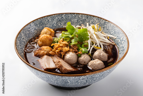 Delicious bowl of Kuay Tiew Reua with meatballs and toppings beautifully presented in traditional bowl