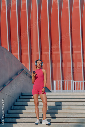 Athlete enjoying outdoor workout while listening to music near modern building
