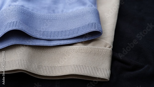 Cuadro en lienzo A close-up of elastic waistbands in beige and blue on jersey underwear garments on black textile background
