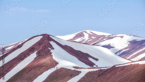 Photography Smooth snow-covered ridges create abstract geometric forms across the high mountains under a clear blue sky in Uzbekistan
