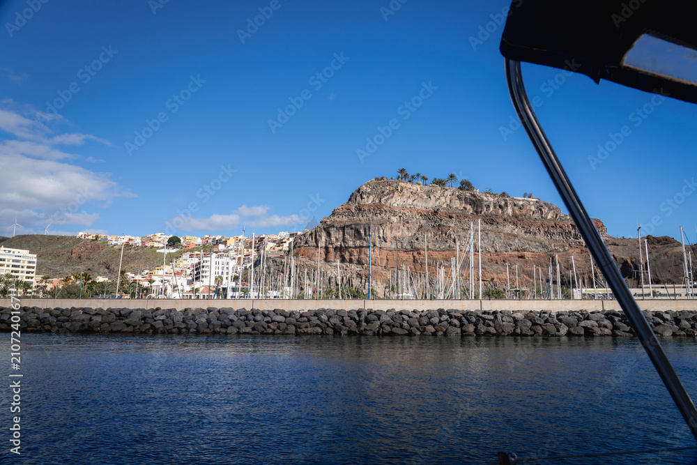Fototapeta premium The town of San Sebastian de La Gomera and its dramatic cliff seen from a boat leaving the marina Canary Islands