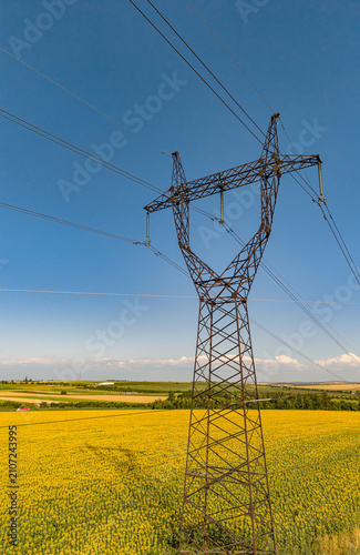 Foto Metal electricity pylon in agricultural field, high voltage power line transmiss