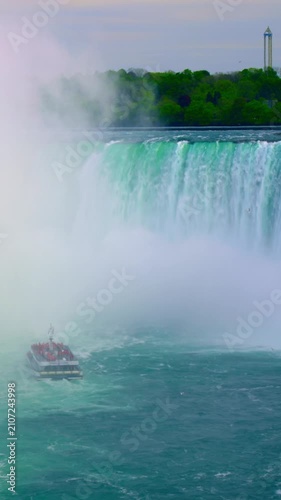 Tiny boat amidst waterfall. Tourist vessel faces cascading spray. Photographer captures massive waterfall and boat movement. Small boat under rushing waterfall experiences spray and mist