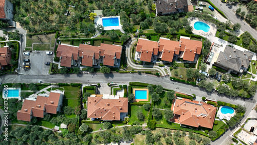 Drone view of Lake Garda in Italy showing houses, pools, and greenery from above