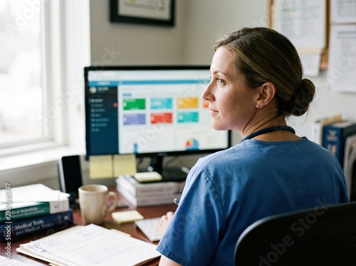Caucasian Doctor Glancing at AI Diagnostic Dashboard on Monitor