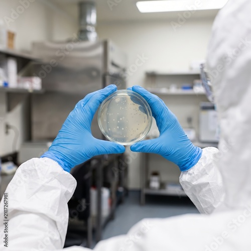 Researcher in Cleanroom Suit Examining Petri Dish Sample