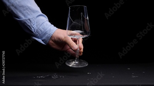 Photography Hand with a blue shirt sleeve holding a wine glass with a broken bowl and stem,